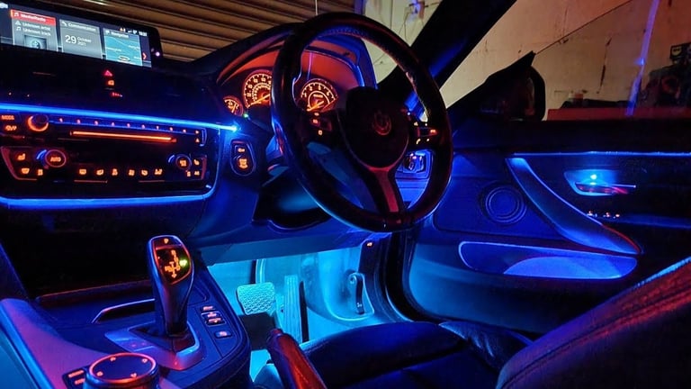 Car interior with blue and red neon lighting, illuminated dashboard, steering wheel, and shift knob at night